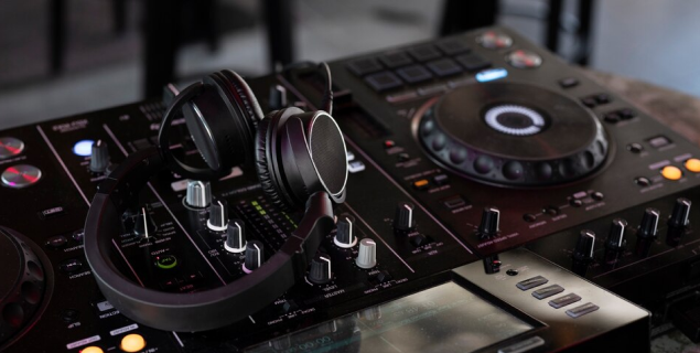 A DJ mixer on the table with headphones on top