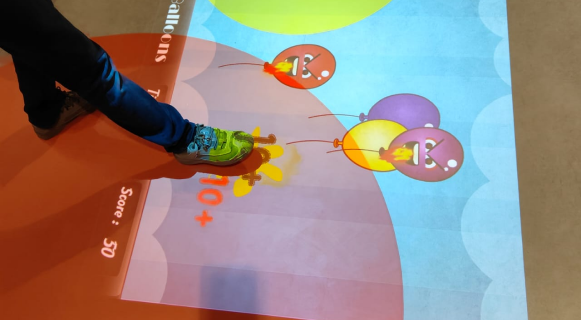 An intreactive floor projector, a kid places ther foot on the projection while the projector responds to it
