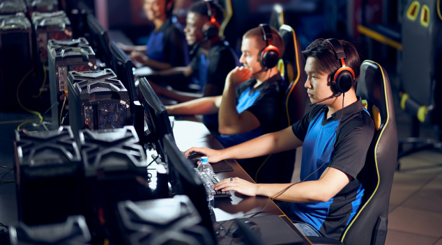 Esports players in a competitive gaming arena using headsets and high performance PCs during a tournament