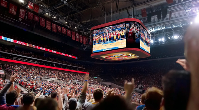 Packed stadium with fans cheering under central 4K video scoreboard and dynamic audio visual system