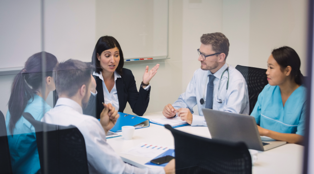 Medical team and consultants having a discussion in a meeting room with documents and laptops around the table