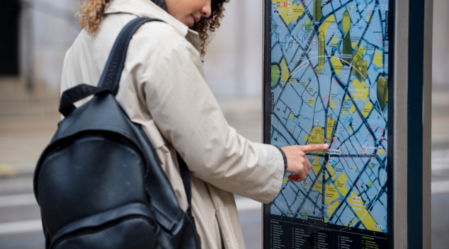 Woman using digital wayfinding map display for navigation at large public venue or arena